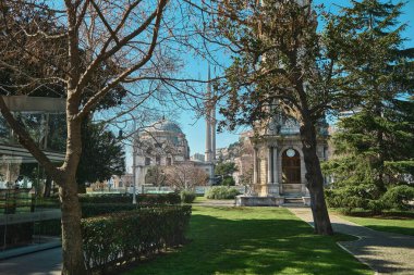  04.03.2021 İstanbul Türkiye. Dolmabahçe Sarayı 'ndan yeşil çimenler ve eski ağaçlar Dolmabahçe Camii' ni gösteriyor. Güneşli bir günde İstanbul Boğazı yakınlarındaki Barok ve eski Osmanlı mimari camisi.