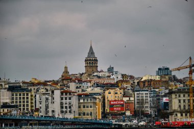 04.03.2021. Hindi İstanbul. Bulutlu ve yağmurlu bir günde ünlü galata kulesi yerel dairelerin ve binaların arkasındaki Eminonu bölgesinden fotoğraf çekerek ve ticari reklam panosuyla birlikte.