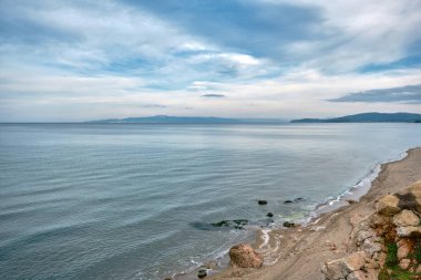 Muhteşem deniz ve doğa manzarası muhteşem bulutlar ve küçük tepeler. Ufuk mavi gökyüzü ve turkuaz renk denizini ayırır.