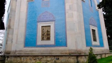 29.03.2021. Bursa hindisi. Yeşil mezar (Yesil Türbe) ve iznik çömlek (cini) veya mezar duvarı ile kaplı fayanslar. Mezarın kapısı, Osmanlı İmparatorluğu 'nun erken dönemlerinde kurulmuş ağaç ve merdivenlerin arkasında.