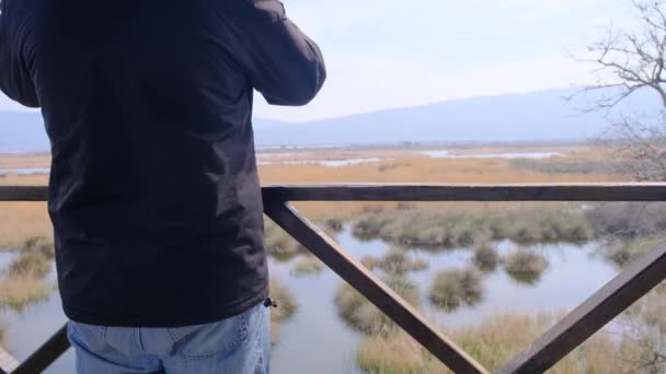 一名男子从观鸟塔俯瞰卡拉卡比的洪泛区 他摘下绿色的医疗面罩 原因是眼镜蛇大流行 然后步行返回 观察到山 沼泽地 水等自然景观 — 图库视频影像