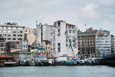 03.03.2021 İstanbul Türkiye. İstanbul 'un Karaköy kıyısı ve İstanbul' da bulutlu ve yağmurlu bir günde küçük balıkçı teknesiyle altın boynuz ile demirlemiş birçok yaya feribotu..