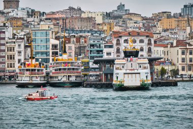03.03.2021 İstanbul Türkiye. İstanbul 'un Karaköy kıyısı ve İstanbul' da bulutlu ve yağmurlu bir günde küçük balıkçı teknesiyle altın boynuz ile demirlemiş birçok yaya feribotu..