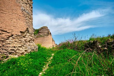 Nicaea 'daki eski ve antik şehir duvarı (iznik Bursa) Bizans tarafından yıkıntı ve taş mezarlarla kurulmuş, güneşli bir günde yeşil çimenler ve sarı çiçekler ve büyük çimenler boyunca uzanan küçük patika..