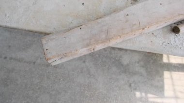 Masanın üzerinde ahşap bir parça ve ahşap ve kırmızı renkli tutacağı var..