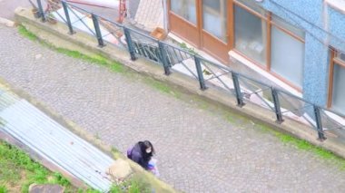 29.03.2021. Bursa hindisi. Bulutlu ve yağmurlu bir günde Tophane bölgesinin hava görüntüsü. Bekar bir kadın alışveriş torbaları taşıyarak apartman ve kaldırım taşları yolunda yürüyor..