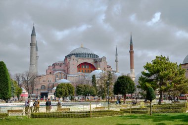 Hagia Sou 'nun üzerindeki bulutlu ve bulutlu hava. Sultanahmet Meydanı 'ndan fotoğraf çekerek Antik haj camii ve bir çok insan ve turistin yürüdüğü yeşil çimenler. 04.03.2021 İstanbul. Türkiye.