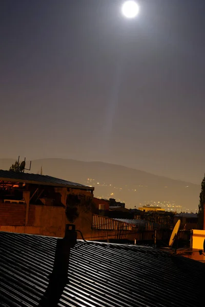 在伯莎午夜的满月 富鲁山 Uludag 和城市照明背景下的棚户区金属屋顶上的月光反射 — 图库照片