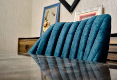 Minimalist tarzlı bir ev. Koltuğun tepesinde ve parlayan ahşap masa yüzeyinde aynalı dokulu duvarlar ve çerçeveli makrome masalar var..