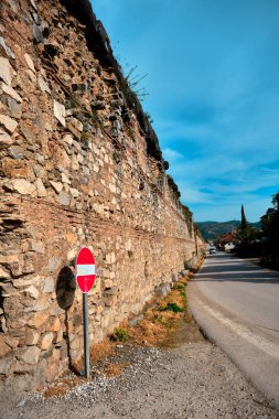 İznik şehir duvarı (Nicaea) kırmızı tuğlalar ve izinsiz giriş uyarısı ve tahtadan yapılmıştır. Roma duvarlarının antik ve harabelerinde yol ve alfabeyle gelen araba ve mavi gökyüzü ile birlikte asılıdır. 27.04.2021 iznik Türkiye.