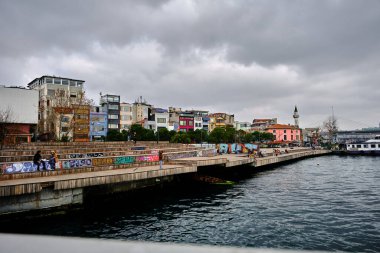 Türkiye istanbul 03.03.2021. Karaköy kıyısı ve oturma alanı üzerinde renkli bir tablo ve İstanbul 'da altın boynuz, boğaz ve genç çiftlerin konuştuğu balıkçı oltasıyla bekleyen bir adam.