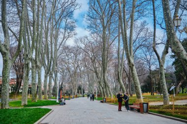 Gulhane parkında yol ve patika beyaz sokak lambaları ve solmuş ve kurumuş ağaçlar ve yeşil çimenler bulutlu gökyüzü, yağmur ve bosporus arka plan boyunca.
