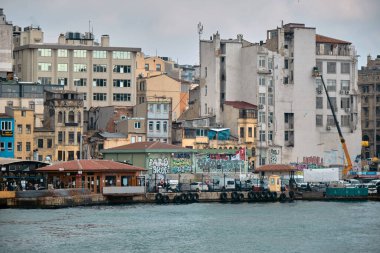 03.03.2021 İstanbul Türkiye. İstanbul 'un Karaköy kıyısı ve İstanbul' da bulutlu ve yağmurlu bir günde küçük balıkçı teknesiyle altın boynuz ile demirlemiş birçok yaya feribotu..