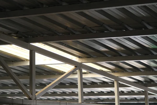 Bottom side of a metal roof and construction frame made of profile metals and white color.