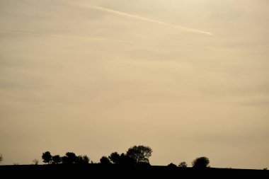 Gün batımı gökyüzü ve küçük tepe. Tepenin silueti ve gökyüzündeki ağaçlar Bursa hindisi içinde.