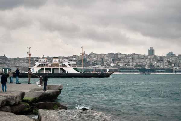 04.03.2021 İstanbul Türkiye. Sarayburnu yakınlarındaki Bosporus istanbul 'dan geçen yaya feribotu bulutlu havalarda deniz kıyısında yürüyen ve balıkçılık yapan bir sürü insanla birlikte.
