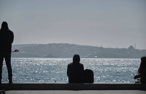 男と女が立ち並んでイスタンブールの裏側の港に腰を下ろして — ストック写真