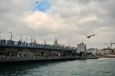 04.03.2021 İstanbul hindisi. Bulutlu ve yağmurlu bir günde Eminonu 'dan İstanbul' da altın boynuz (halik) fotoğrafı. Martı ve kule arkaplanlı bulutlu havada Galata Köprüsü.