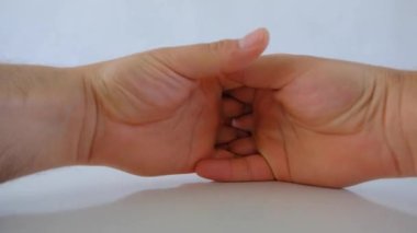 Bir adam el işareti bekliyor ve parmaklarını beyaz ve parlak masa yüzeyine koyuyor ve parmakları beyaz zeminde yansıyor..