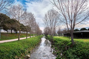 Bursa 'da büyük ve kurumuş ağaçlarla kaplı küçük bir nehir. Koşan, yürüyen patikalar, insanlar ve gün batımında köprü altyapısı olan bir nehir.. 
