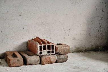 Beyaz beton, alçı duvar ve zemin üzerine kırmızı tuğla yığını. Çeşitli kırmızı ve yerde kullanılmış tuğlalar.