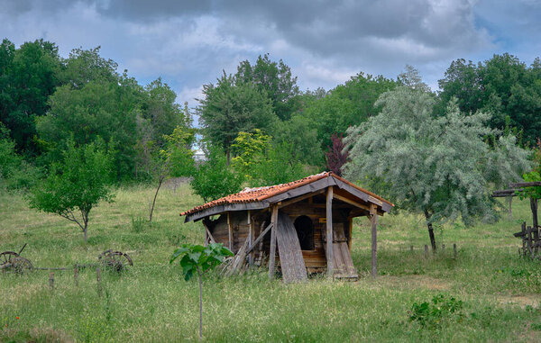 Old abandoned and brownfield village home with green grass and it is established on stone ground in nature with huge clouds background with overcast day
