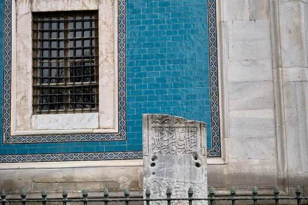 29.03.2021. Bursa Turkey. Tombstone or gravestone written by arabic letters in ottoman language in Bursa green tomb (Yesil Turbe) with iznik pottery (cini) covered tomb wall and window background.