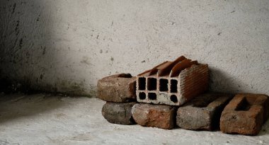 Beyaz beton, alçı duvar ve zemin üzerine kırmızı tuğla yığını. Çeşitli kırmızı ve yerde kullanılmış tuğlalar.
