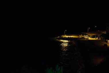 Geceleri Mudanya limanında şehrin ışık yansıması olan küçük bir liman. Liman ve şehir ışıklarında Fiat Dobla park yeri. Bursa Türkiye 21.08.2021