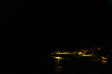 Geceleri Mudanya limanında şehrin ışık yansıması olan küçük bir liman. Liman ve şehir ışıklarında Fiat Dobla park yeri. Bursa Türkiye 21.08.2021