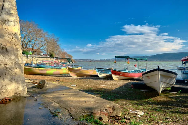 Kolorowe Łodzie Stojące Wybrzeżu Jeziora Uluabat Starym Miastem Ogromnym Tłem — Zdjęcie stockowe