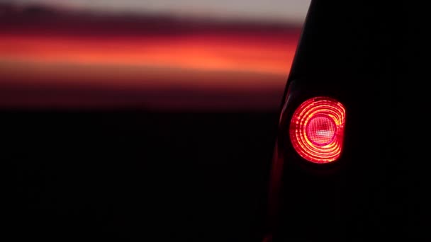 Intermitente luz trasera del coche en la puesta del sol — Vídeo de stock