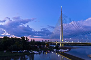 Belgrad, Sırbistan 'daki Ada adası yakınlarındaki Sava nehrinin üzerindeki alacakaranlıktaki kablolu köprü