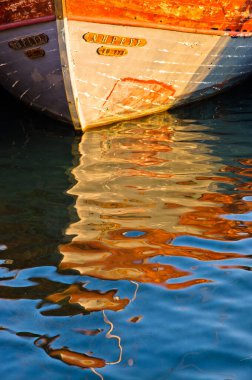 Günbatımında, Porto Koufo, Sithonia, Yunanistan, denizde sıvı renk soyutlaması olarak görülen bir teknenin renkli yansıması