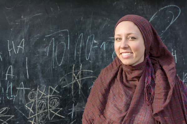 Счастливый учитель в хиджабе перед школьной доской — стоковое фото