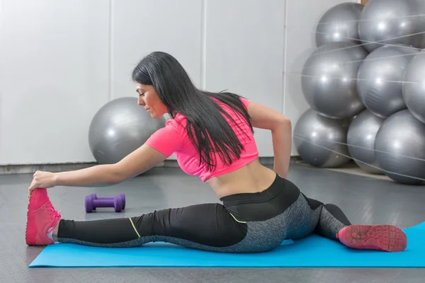 Brunette die zich uitstrekt op een mat — Stockfoto