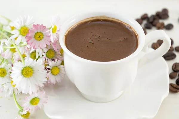Чашка кави на столі, прикрашена квітами — стокове фото