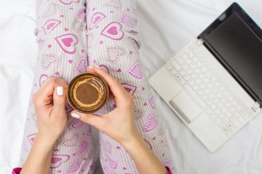 Woman having a cup of coffee in bed clipart