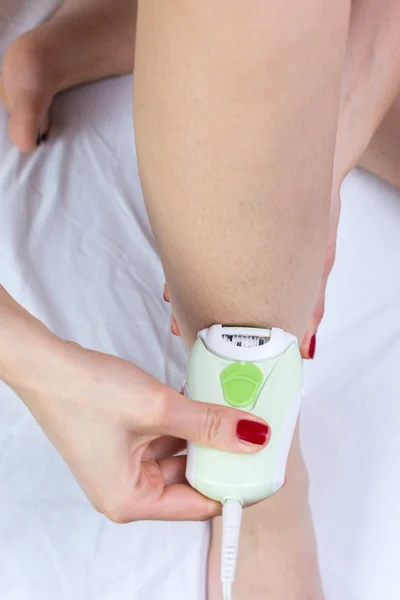 Girl epilates her leg with an epilator — Stock Photo, Image