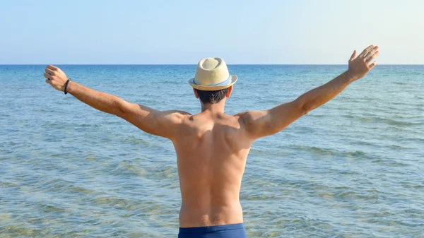 Mies levittää käsiään meren rannalla. — kuvapankkivalokuva