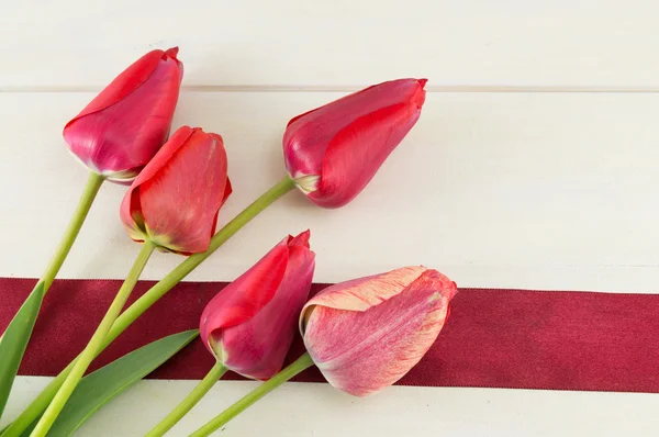 Tulipanes rojos sobre una mesa de madera — Foto de Stock