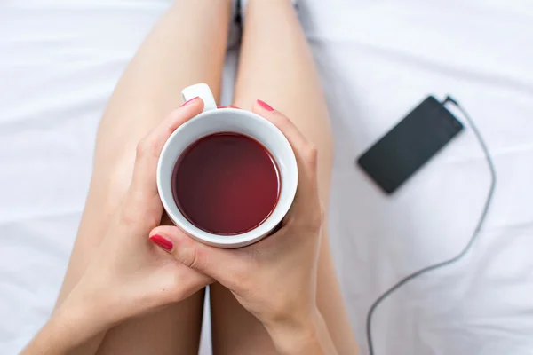 Mujer con taza de té en la cama —  Fotos de Stock