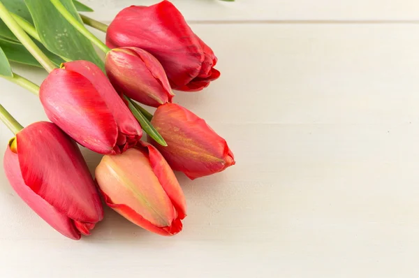 Tulipanes rojos sobre una mesa de madera — Foto de Stock