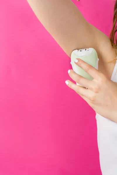 Woman epilates her armpit with an epilator — Stock Photo, Image