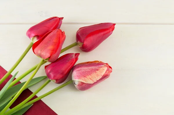 Tulipanes rojos sobre una mesa de madera — Foto de Stock