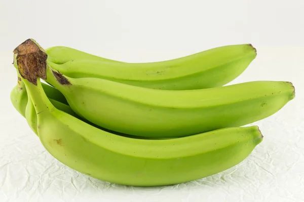 Зеленые бананы на белой ткани — стоковое фото