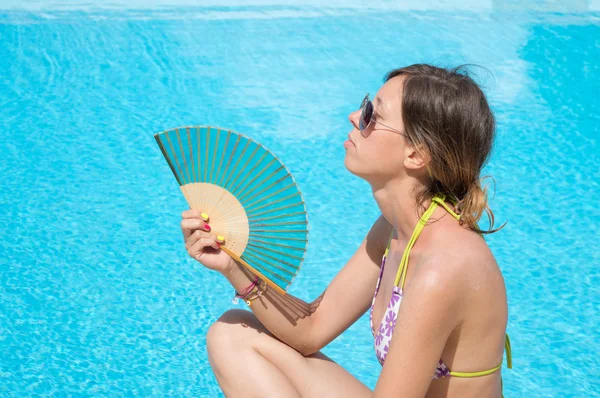 Girl with a traditional hand fan by the pool — Stock Photo, Image