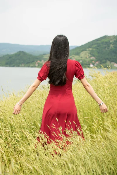 Girl in a wheat field wearing red dress — Stock Photo, Image