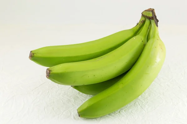 Зеленые бананы на белой ткани — стоковое фото