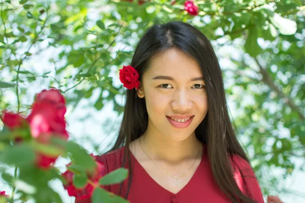 Kobieta w czerwonej sukience z red rose w jej włosy — Zdjęcie stockowe